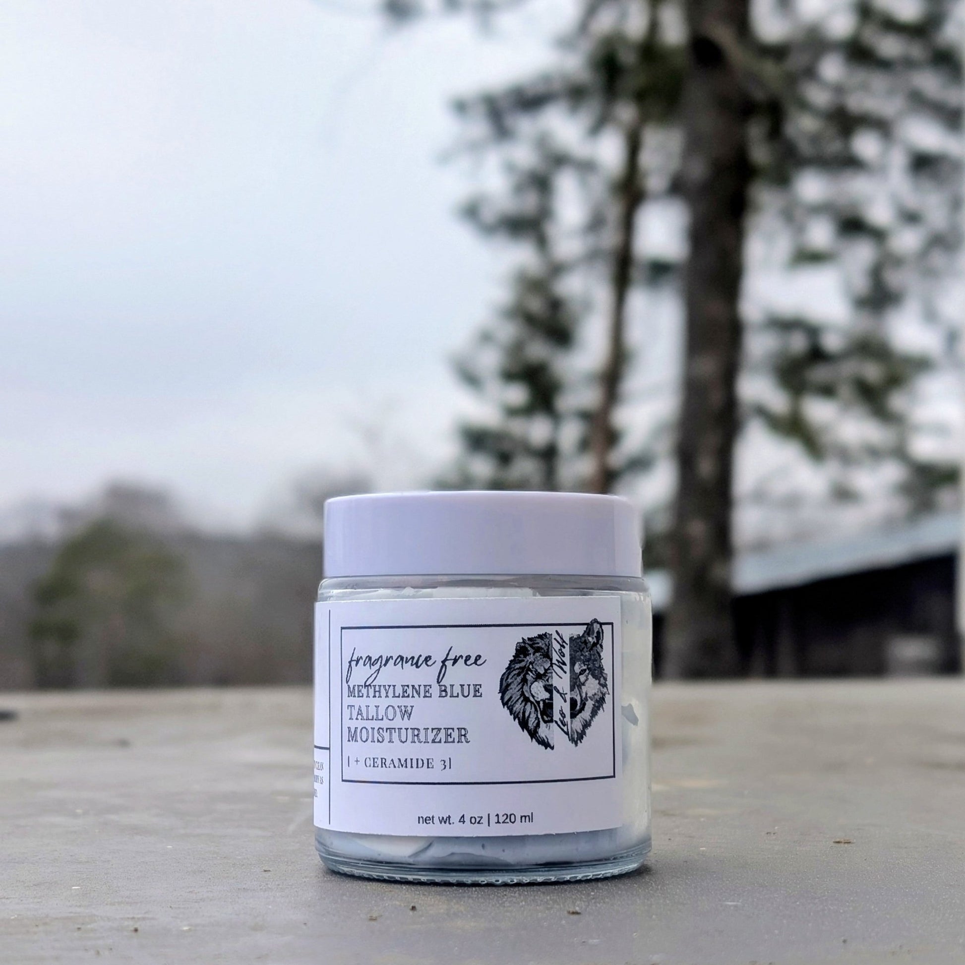 Jar of lotion on a wooden surface with trees in the background