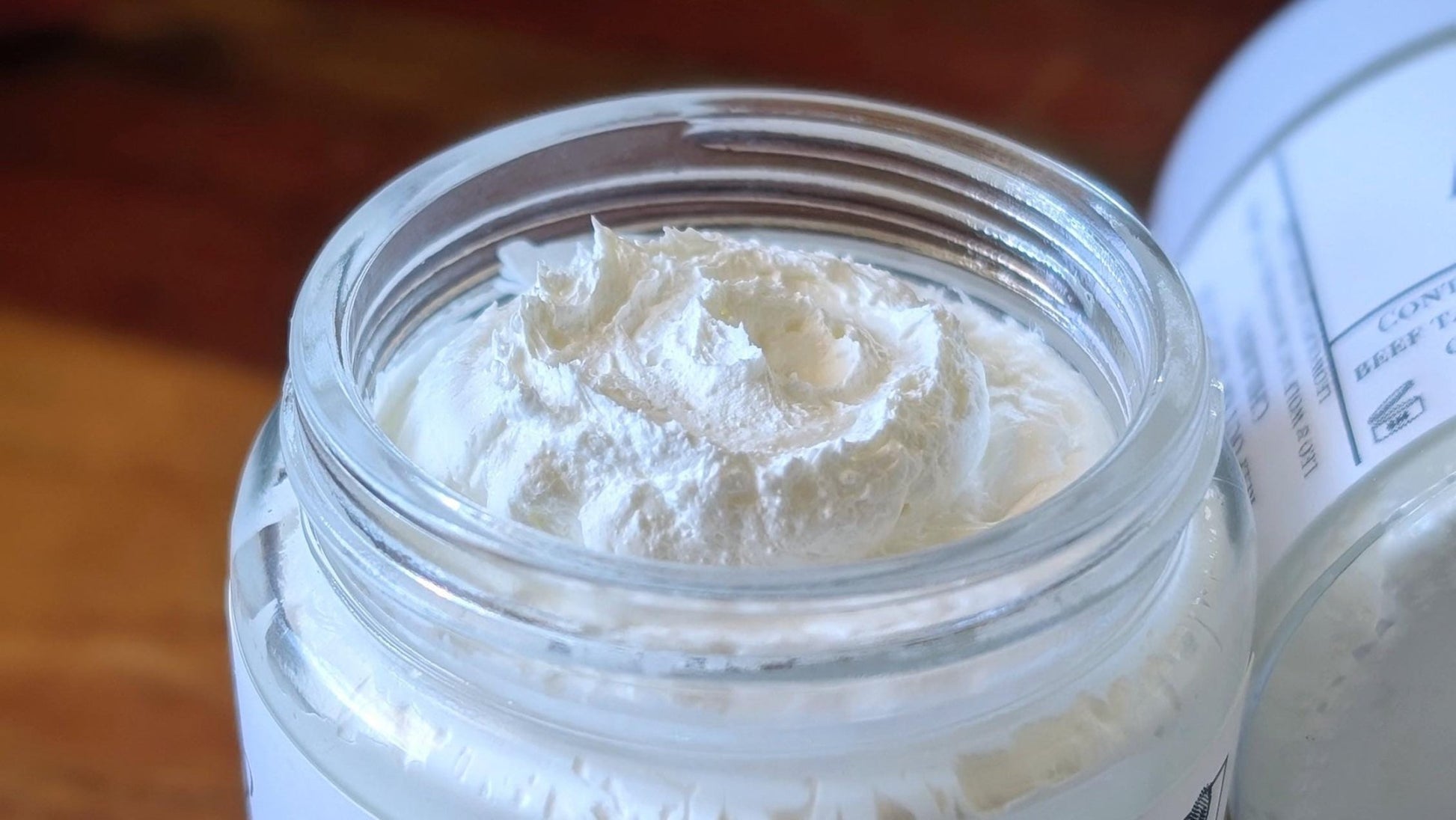 Jar of Whipped Tallow Sun Cream on a wooden surface