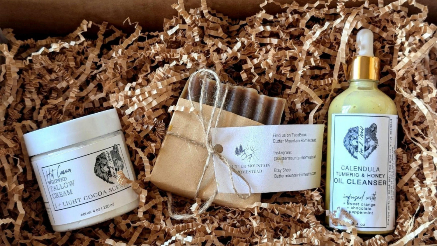 Skincare products including a cream, soap bar, and oil cleanser in a box with crinkled paper