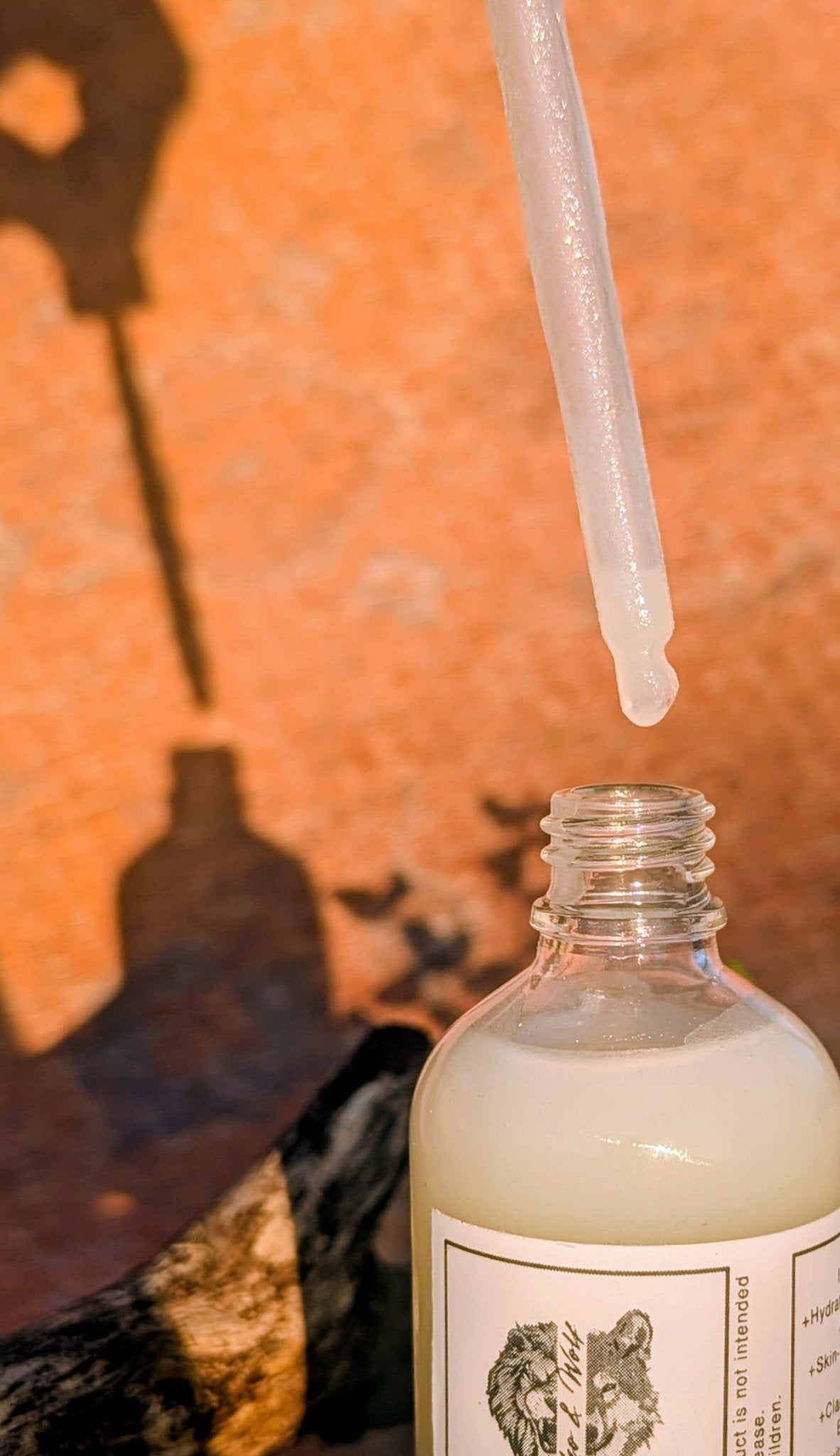 Glass bottle with dropper on an orange background